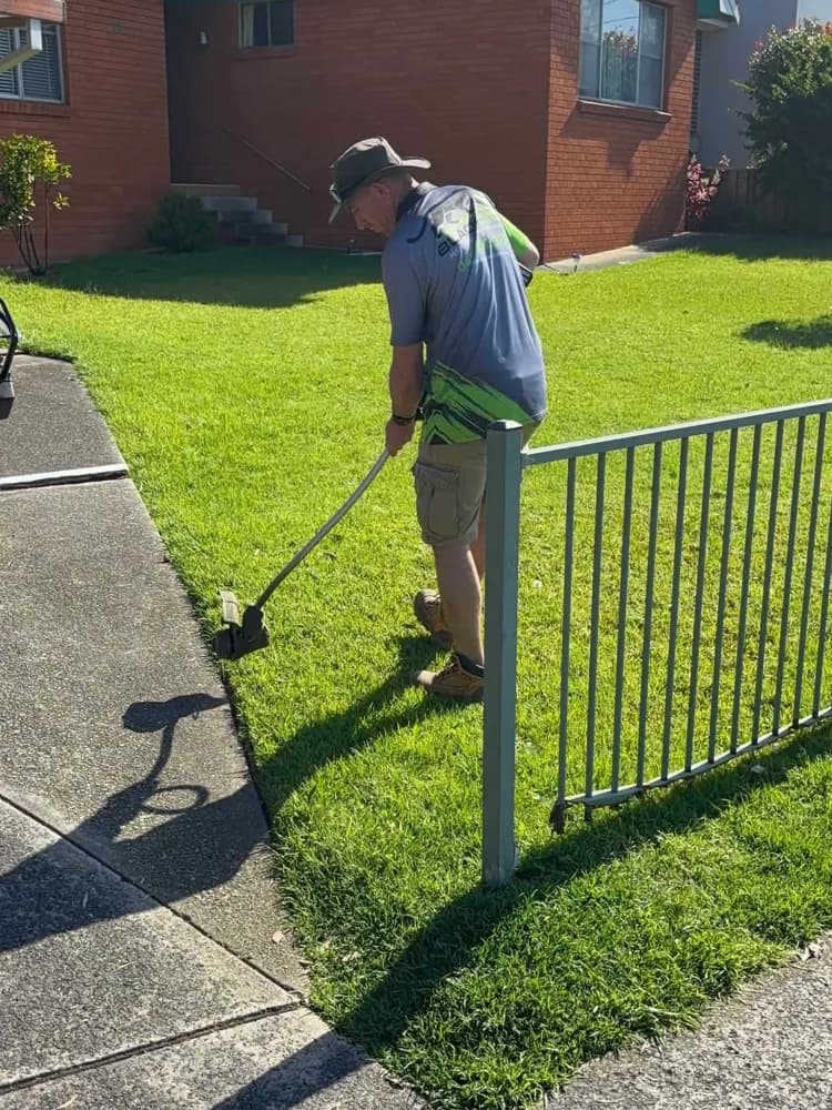 Wayne edging a lawn along a fence line in Western Sydney