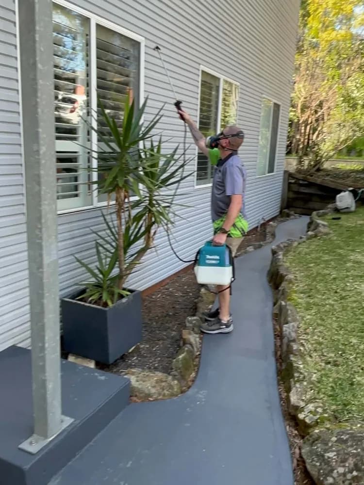 Wayne treating the eaves of a home with a backpack sprayer